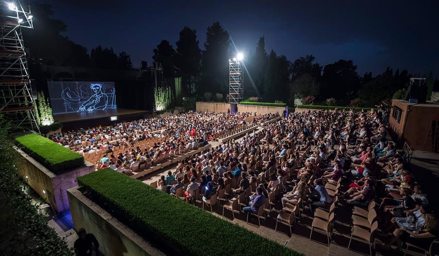 Un anfiteatro al aire libre reúne a un numeroso público durante una representación nocturna